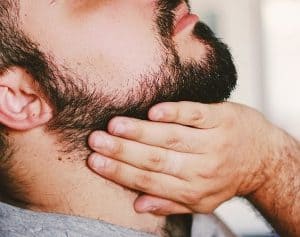 hombre poniendo aceite para la barba en la barba