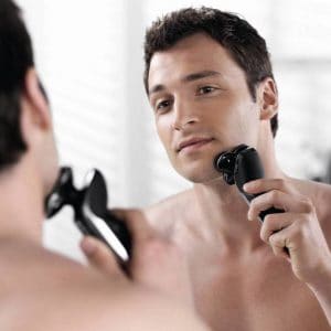 hombre usando máquina de afeitar eléctrica moderna