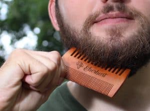 hombre usando un peine para la barba de madera