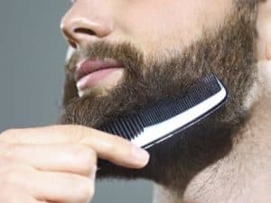 hombre joven peinándose la barba con un peine para la barba