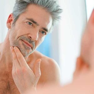 adulto poniéndose crema facial antiarrugas para hombre