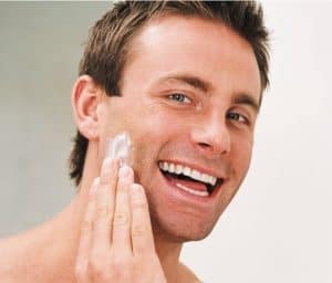 hombre poniéndose crema facial antiarrugas en la cara